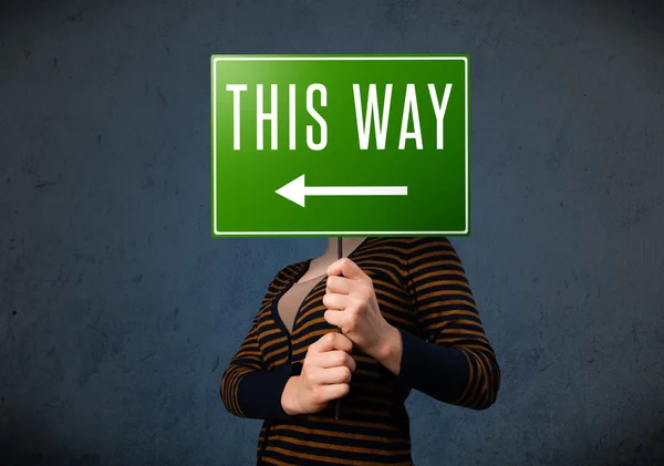 Young woman holding a direction sign — Stock Photo, Image