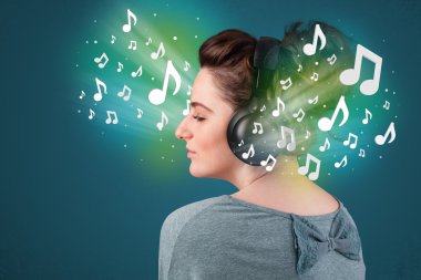 Kulaklıklı genç bir kadın müzik dinliyor.
