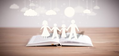 Ailenin karton figürleri açık bir kitabın üzerinde.