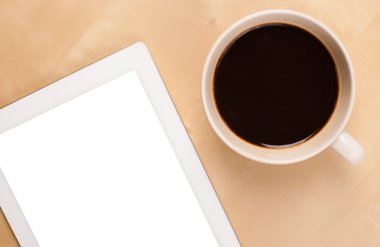 Boş alanı olan bir tablet bilgisayar ve masada bir fincan kahve.