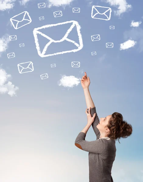 Chica joven mirando el símbolo de correo nubes en el cielo azul — Foto de Stock