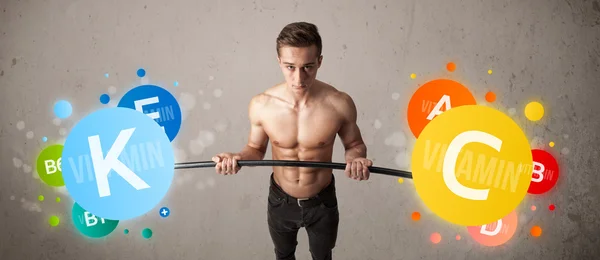 Muscular man lifting colorful vitamin weights — Stock Photo, Image