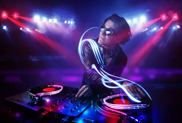 Discjockey som spelar musik med ljusstrålen effekter på scenen — Stockfoto