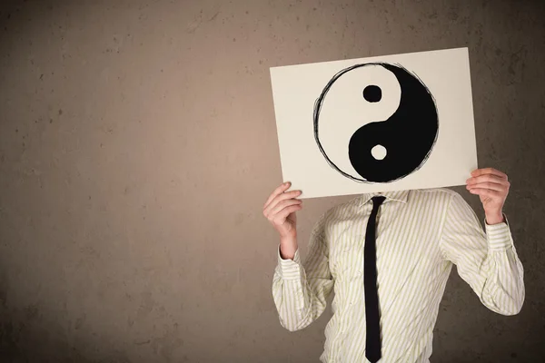 Businessman holding a paper with a yin-yang on it in front of hi — Stock Photo, Image