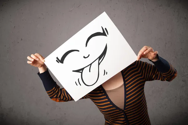 Woman holding a paper with cute smiley face on it in front of he — Stock Photo, Image