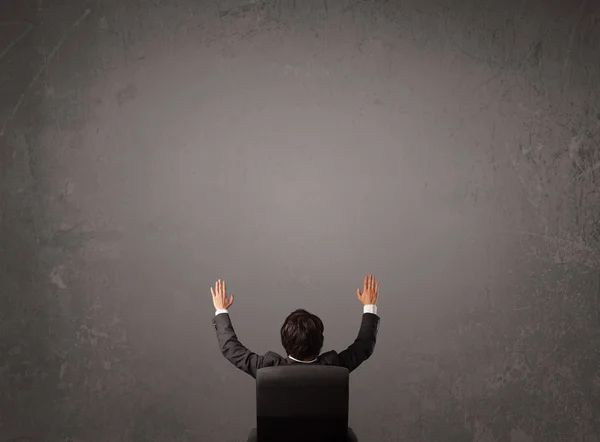 Businessman sitting in front of a wall with copy space — Stock Photo, Image