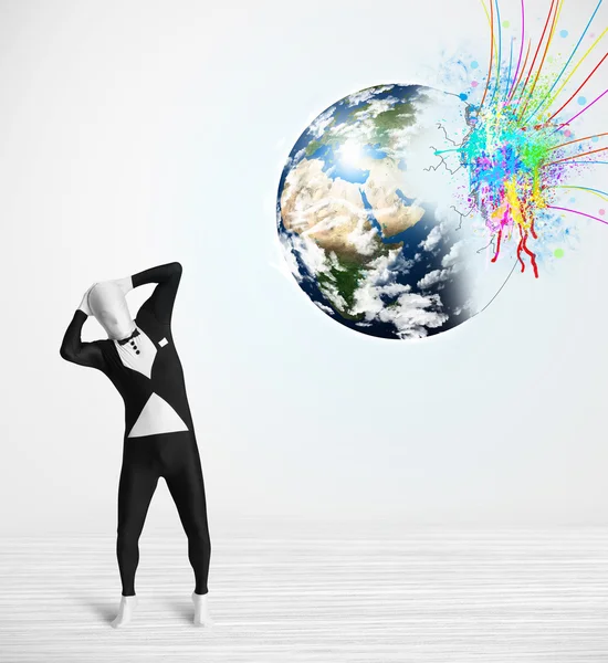 Funny man in body suit looking at colorful splatter earth — Stock Photo, Image