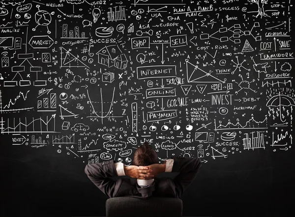 Empresário sentado na frente de um quadro negro com gráficos — Fotografia de Stock