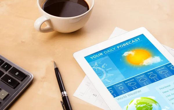 Tablet pc showing weather forecast on screen with a cup of coffe — Stock Photo, Image