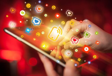 Sosyal medya simgelerine sahip tablet kullanan bir elin yakın plan görüntüsü