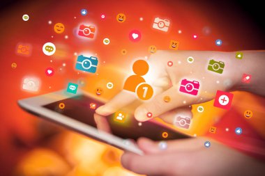 Sosyal medya simgelerine sahip tablet kullanan bir elin yakın plan görüntüsü