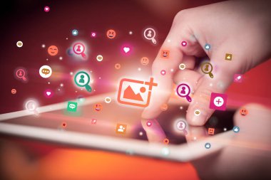 Sosyal medya simgelerine sahip tablet kullanan bir elin yakın plan görüntüsü