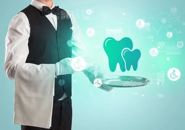 Handsome young waiter in tuxedo holding healthcare icons on tray — Stock Photo, Image