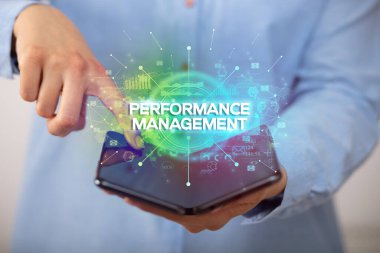 İş adamı katlanabilir bir akıllı telefon tutuyor Performans MANAGEMENT yazıtları, yeni iş konsepti