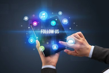 FOLLOW ABD yazıtları ve sosyal medya kavramına sahip katlanabilir bir akıllı telefon tutan iş adamı