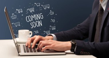 İş adamı dizüstü bilgisayarda Coming Soon yazıtı ve online alışveriş konseptiyle çalışıyor.