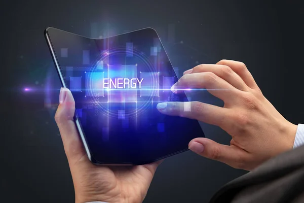エネルギー碑文 新しい技術の概念と折り畳み式のスマートフォンを保持ビジネスマン — ストック写真