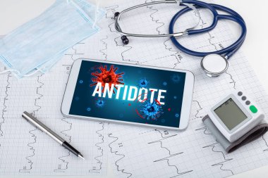 Beyaz yüzeyde ANTIDOTE yazıtı, salgın konsepti içeren tablet pc ve doktor araçları