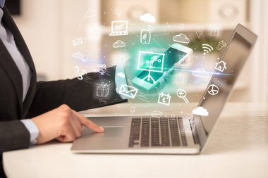 Dizüstü bilgisayarda çalışan iş adamı, içinden resim çizelgeleri çıkıyor, iş dünyası kavramı büyüyor.