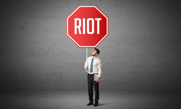 Riot Felirattal Ellátott Útjelzéssel Rendelkező Fiatal Üzletember Szabálykoncepció — Stock Fotó