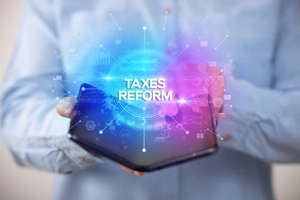 Empresário Segurando Smartphone Dobrável Com Inscrição Taxes Reform Novo Conceito — Fotografia de Stock