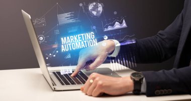 İş adamı, pazarlama otomasyon yazıtları ve yeni iş konseptiyle dizüstü bilgisayarda çalışıyor.