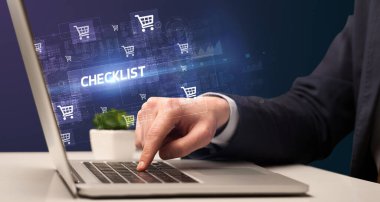 İş adamı, CHECKLIST yazıtları ve online alışveriş konseptiyle dizüstü bilgisayarda çalışıyor.