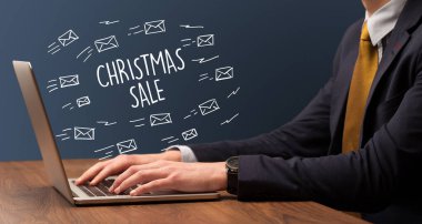 Yılbaşı indirimi ve online alışveriş konseptiyle dizüstü bilgisayarda çalışan bir işadamı.