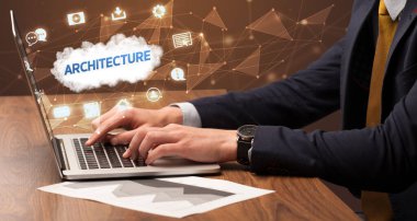 Mimari yazıtlar ve modern teknoloji konseptiyle dizüstü bilgisayarda çalışan bir iş adamı.