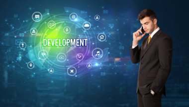 Teknolojiyle ilgili ikonlar ve DEVELOPMENT yazıtları ve modern teknoloji kavramı önünde düşünen iş adamı
