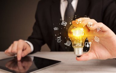 Elinde VLOG yazılı ampul tutan bir iş adamı, sosyal medya kavramı