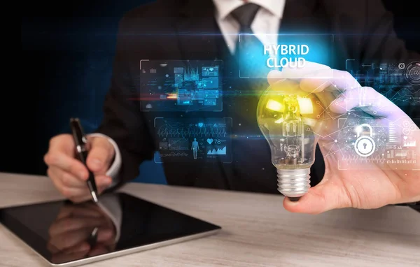 ハイブリッドクラウドの碑文と電球を保持ビジネスマン オンラインセキュリティのアイデアのコンセプト — ストック写真