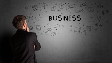 İş adamı, BUSINESS yazıtları ve iş stratejisi konseptiyle yaratıcı bir fikir çizimi yapıyor.