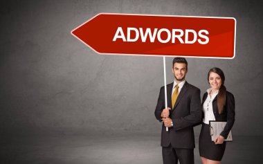 Üzerinde ADWORDS yazıları, yeni iş yönü konsepti olan günlük bekleme yolu tabelasında genç bir iş adamı