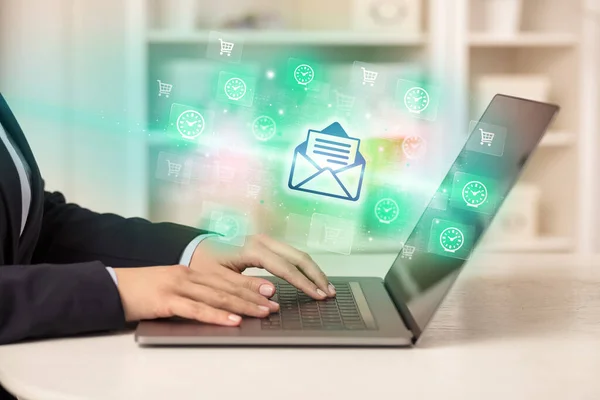 Businessman working on laptop with mail icons coming out from it, successful business concept