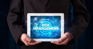 Tablet üzerinde çalışan genç iş adamı ve yazıyı gösteriyor: RISK MANAGEMENT, iş konsepti