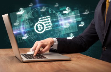 İşadamı, bilgisayar ekranından çıkan bitcoin tasarruf simgeleriyle borsada çalışıyor