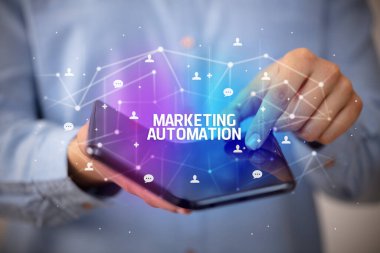 İş adamı elinde pazarlama otomasyon yazısıyla katlanabilir bir akıllı telefon tutuyor, yeni teknoloji konsepti