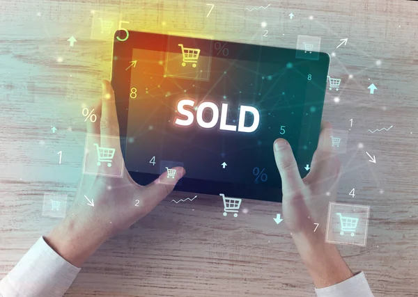 Close-up of a hand holding tablet with SOLD inscription, online shopping concept