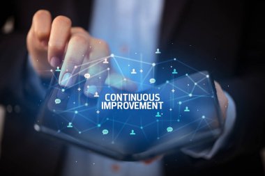 Katlanabilir akıllı telefonu elinde tutan bir iş adamı. Üzerinde sürekli geliştirme yazıları ve yeni teknoloji kavramı var.