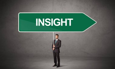 Genç iş adamı, içinde INSIGHT yazıtları ve yeni iş yönü kavramı olan günlük bekleme yolu tabelasında.