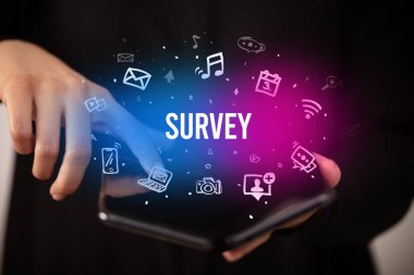 İş adamı elinde katlanabilir bir akıllı telefon tutuyor. Üzerinde SURVEY yazıları, sosyal medya kavramı var.