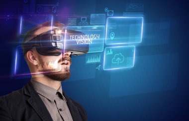 TECHNOLOGY VISION yazıtları ve yeni teknoloji konseptiyle Sanal Gerçeklik gözlüklerine bakan iş adamı