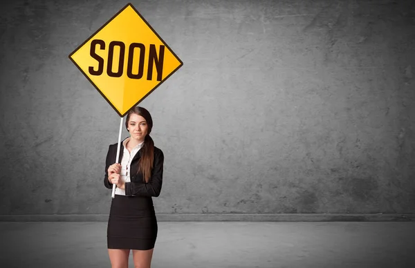 Young business person holding road sign with SOON inscription, new rules concept