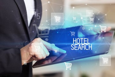 Genç kişi, HOTEL Arama yazısıyla online alışveriş uygulaması üzerinden alışveriş yapıyor