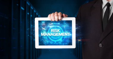 Tablet üzerinde çalışan genç iş adamı ve yazıyı gösteriyor: RISK MANAGEMENT, iş konsepti