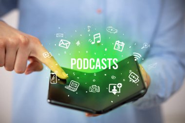 Podcast yazıları ve sosyal medya konsepti olan katlanabilir bir akıllı telefon tutan bir iş adamı