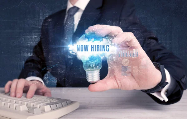 Empresario Sosteniendo Una Bombilla Con Inscripción Now Hiring Nuevo Concepto —  Fotos de Stock