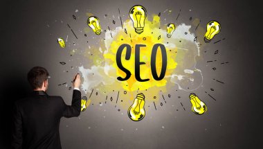 SEO kısaltması ile renkli ampul çizen iş adamı, yeni teknoloji fikri