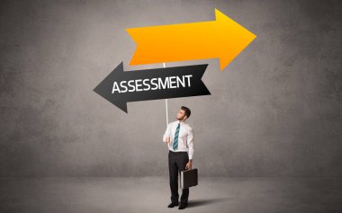 Genç iş adamı, günlük bekleme yolu tabelasında ASSESSMENT yazıtı, iş yönü konsepti